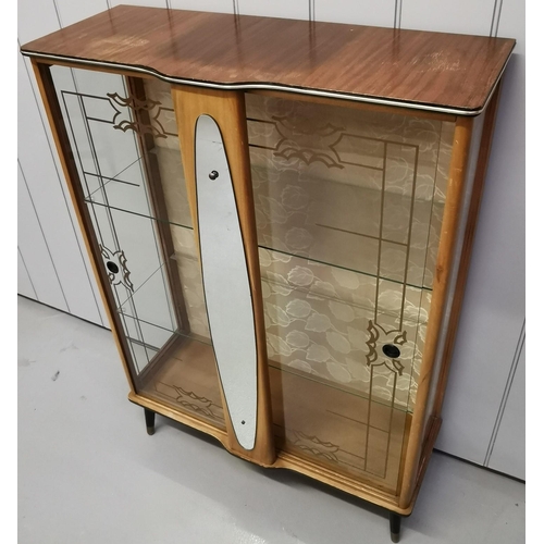 952 - A mid-century cocktail cabinet. Two decorative glass sliding doors aside a mirrored centre column, w... 