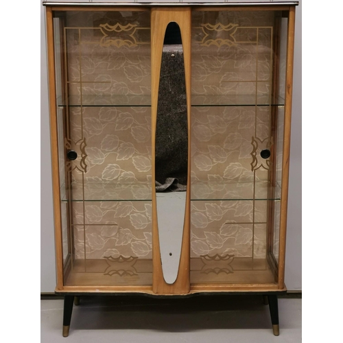 952 - A mid-century cocktail cabinet. Two decorative glass sliding doors aside a mirrored centre column, w... 