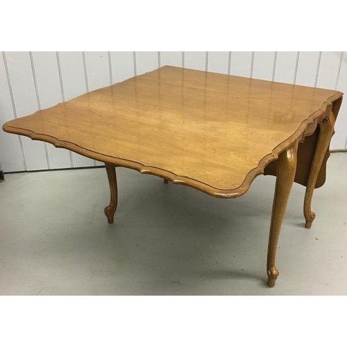 18 - A drop leaf extendable dining table, with a scalloped edge. Multi-extendable, complete with two addi... 