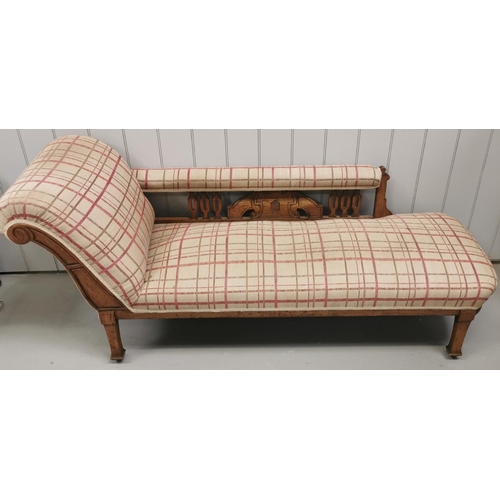 154 - An Edwardian oak chaise longue, upholstered in a beige tartan fabric. Dimensions(cm) H77, W190, D70.