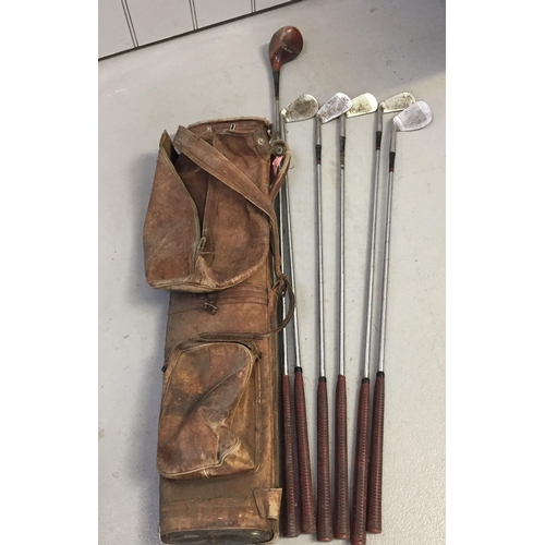 739 - A vintage leather golf bag, with a part-set of clubs. To include a 'Bobby Locke' wood no 2; wedge & ... 