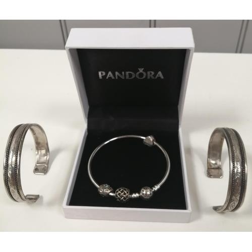 875 - A silver 'Pandora' charm bracelet, with three charms, together with a pair of white metal bangles.