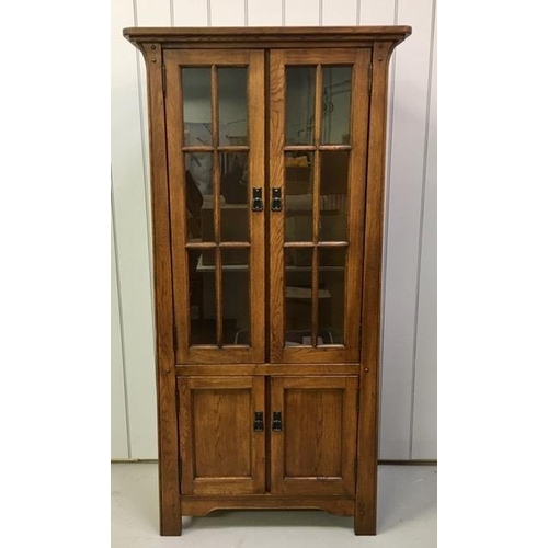 52 - An oak corner display cabinet, with two glass shelves & a single shelved cupboard. PAT test pass & l... 