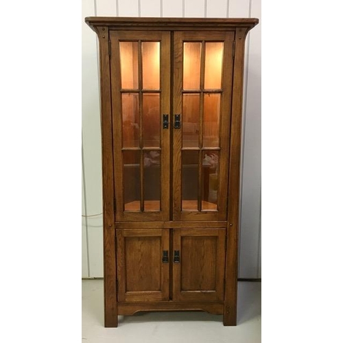 52 - An oak corner display cabinet, with two glass shelves & a single shelved cupboard. PAT test pass & l... 