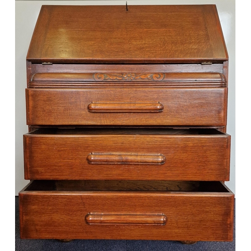 14 - An Edwardian period, oak bureau. Drop-front, partially fitted interior over three graduated drawers.... 