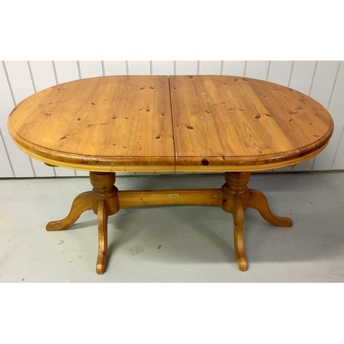 12 - An extending, oval pine dining table. Made by 'Cotswold Collection'. Twin pedestal base, with extens... 