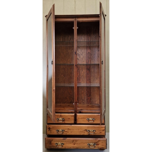 25 - A good quality, dark stained pine display cabinet, with three internal glass shelves & brass fitting... 