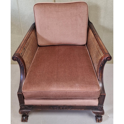 30 - An antique, bergere lounge armchair. Carved detail to armrests & frame, supported by claw & ball fee... 