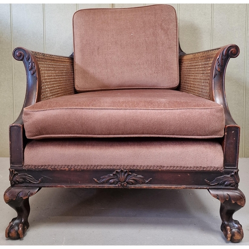 30 - An antique, bergere lounge armchair. Carved detail to armrests & frame, supported by claw & ball fee... 