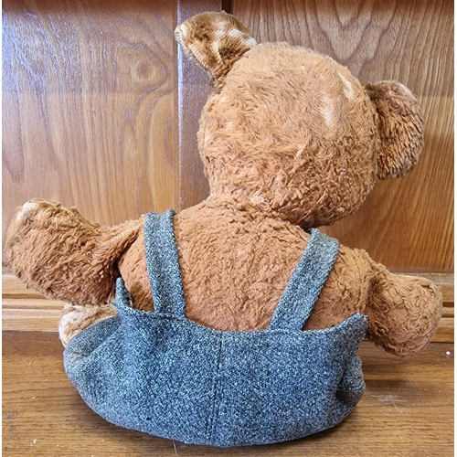 763 - A mid-century teddy bear, in dungarees (likely added later). Height 35cm.