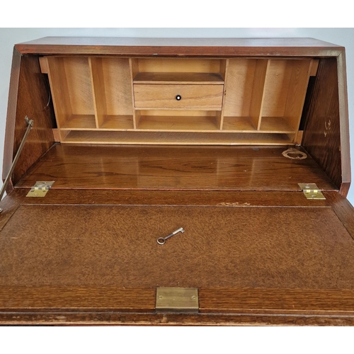 14 - An Edwardian period, oak bureau. Drop-front, partially fitted interior over three graduated drawers.... 