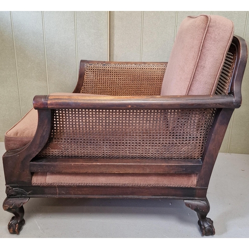 30 - An antique, bergere lounge armchair. Carved detail to armrests & frame, supported by claw & ball fee... 