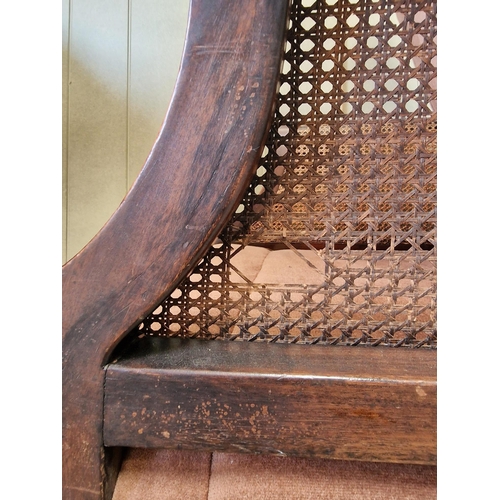 30 - An antique, bergere lounge armchair. Carved detail to armrests & frame, supported by claw & ball fee... 