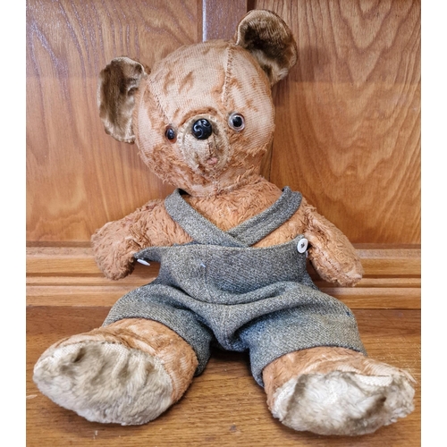 763 - A mid-century teddy bear, in dungarees (likely added later). Height 35cm.