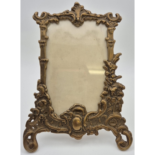 4800 - An ornate, Victorian, brass photo frame, together with an art deco handheld vanity mirror. Respectiv... 