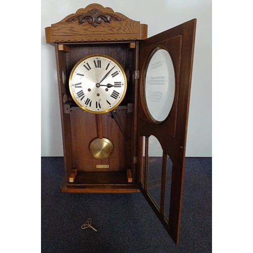 131 - An Arts & Crafts pendulum wall clock. Complete with key. Height 76cm.