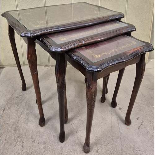 24 - A vintage nest of tables. Leather-topped, with glass protectors. Largest dimensions(cm) H53, W56, D4... 