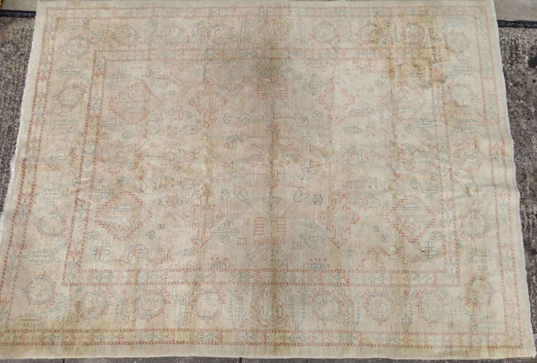 A large, cream rug with Aztec-style pattern. Faded, with signs of wear ...