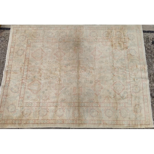 A large, cream rug with Aztec-style pattern. Faded, with signs of wear ...