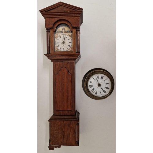 687 - A miniature battery-operated longcase clock, together with a brass port-hole clock. A/F condition.
R... 
