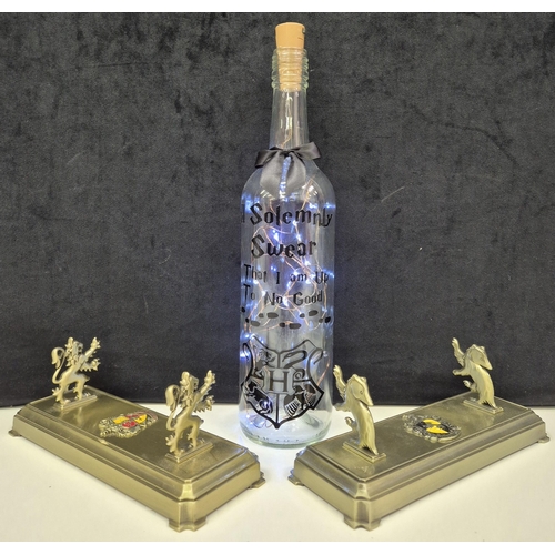 Three Harry Potter themed items. To include bottle light & 2 'Noble Collection' brass wand stands (Gryffindor & Hufflepuff).
