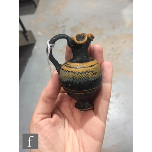 125 - Roman 2nd to 4th Century AD - A miniature dark black glass jug with multi yellow zig zag bands of de... 