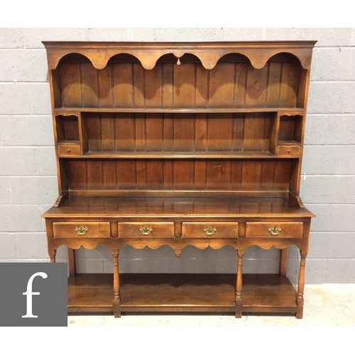 907 - A reproduction oak dresser in the 18th Century style, the upright two-tier plate rack section with a... 