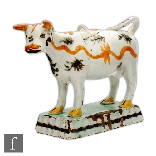 33 - An early 19th Century pearlware cow creamer and cover, she decorated with tan wavy lines and black l... 