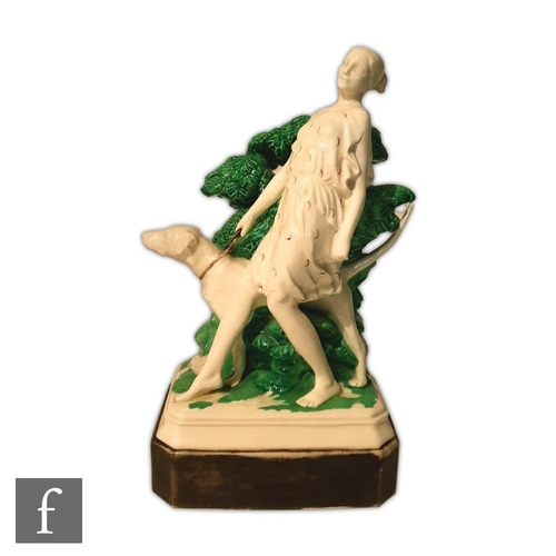 54 - A 1930s model of a lady walking her dog, stood before green foliage, all to a painted black pedestal... 