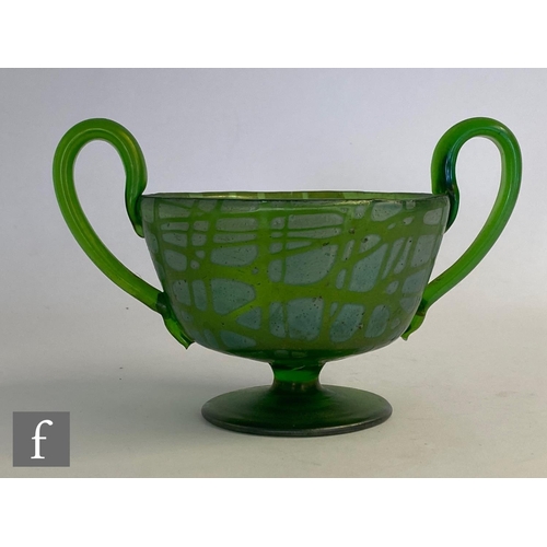 25 - In the manner of Loetz - An early 20th Century glass twin handled pedestal cup in green with a rando... 