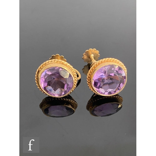 550 - A pair of 9ct single stone amethyst stud earrings, circular stones within a rope twist border to scr... 