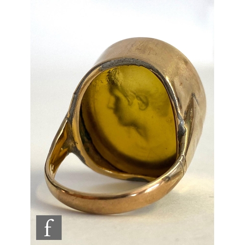 561 - A 9ct ring with central signed amber glass intaglio carved oval depicting head and shoulder profile ... 