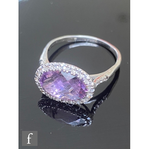 576 - A 9ct amethyst and diamond cluster ring, central faceted cut oval amethyst within a twenty stone dia... 