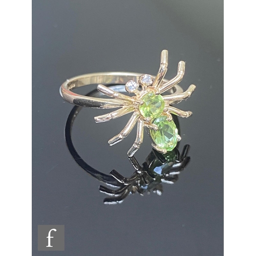 581 - A 9ct hallmarked peridot and diamond spider shaped ring, the two peridot body below diamond set eyes... 