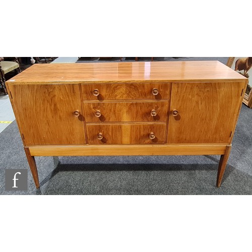 950 - A mid 20th Century walnut veneered sideboard in the manner of Cotswold School, fitted with a central... 