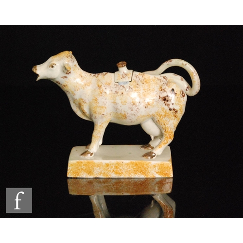 100 - A late 18th to early 19th Century Staffordshire pearlware cow creamer and cover, with ochre and mang... 