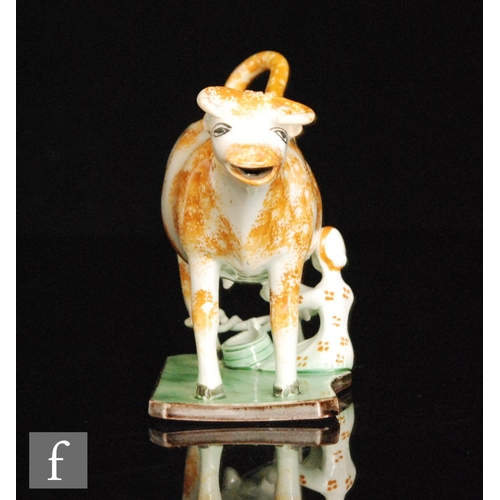 101 - A late 18th to early 19th Century Staffordshire Pratt Ware cow creamer and cover with a seated milk ... 