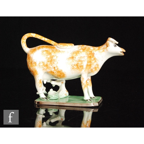 101 - A late 18th to early 19th Century Staffordshire Pratt Ware cow creamer and cover with a seated milk ... 