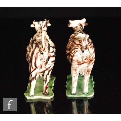 106 - A pair of late 18th to early 19th Century Staffordshire creamware cow creamers and covers, both stoo... 