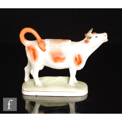 107 - An early 20th Century Royal Dux cow creamer and cover, the cow with brown sponged patches, stood on ... 