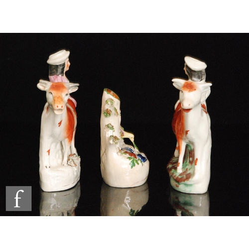 108 - Two mirrored Staffordshire spill vases modelled as facing cows with a lady and gentleman stood behin... 