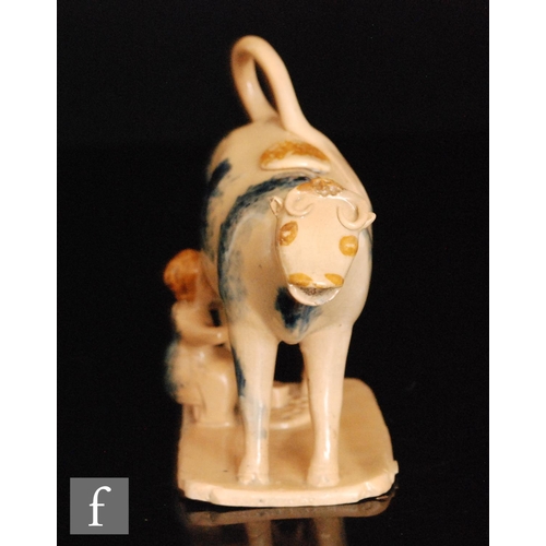 89 - An early 19th Century cow creamer and cover with milk maid and pail beneath, she decorated with blue... 