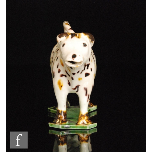 92 - An early 19th Century Staffordshire Prattware cow creamer and cover, decorated with brown and ochre ... 