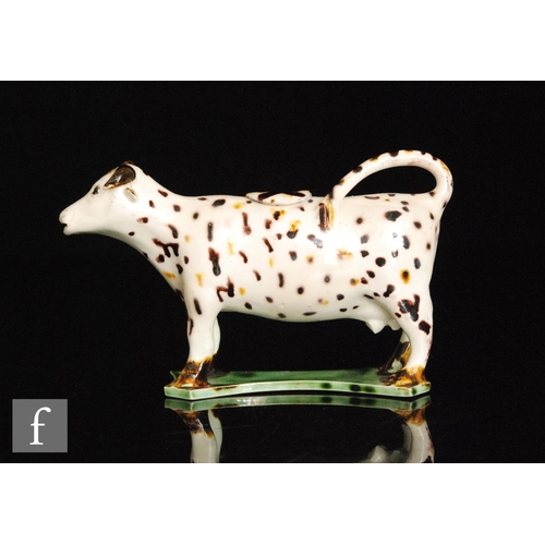 92 - An early 19th Century Staffordshire Prattware cow creamer and cover, decorated with brown and ochre ... 