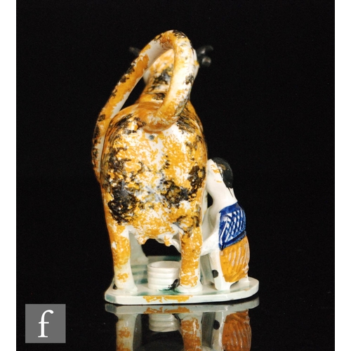 93 - An early 19th Century Staffordshire Prattware cow creamer and cover with milk maid and pail beneath,... 