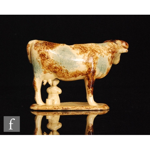 95 - An early 19th Century cow creamer with a milk maid and pail beneath, she decorated with blue green a... 