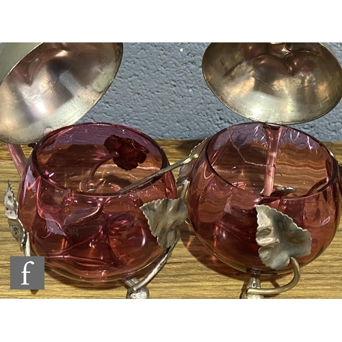 168 - A pair of late 19th Century cranberry glass preserve pots of fluted ovoid form mounted to EPNS frame... 