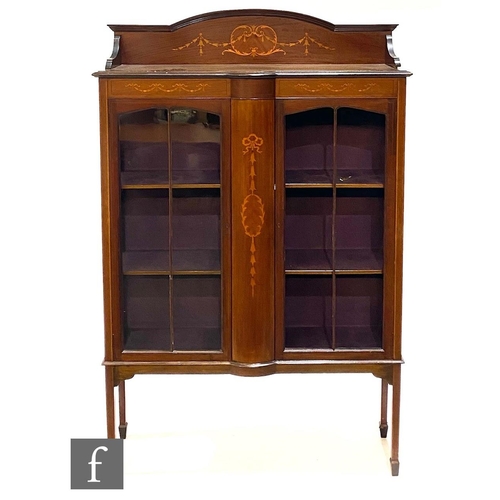 1145 - An Edwardian inlaid mahogany display cabinet enclosed by a pair of bar glazed doors below an arched ... 