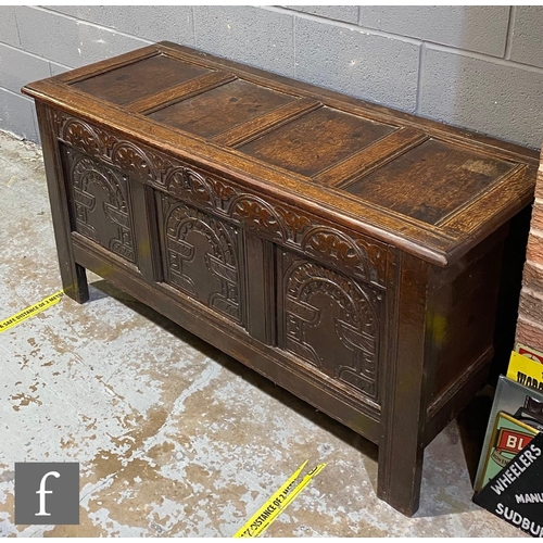 1143 - An 18th Century carved oak coffer, the triple panel arch front below a quadruple panelled top on sti... 