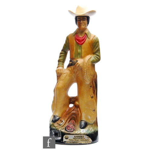 1243 - Regal China Corporation - A 1980s Jim Beam ceramic decanter modelled as a cowboy, with plastic cowbo... 